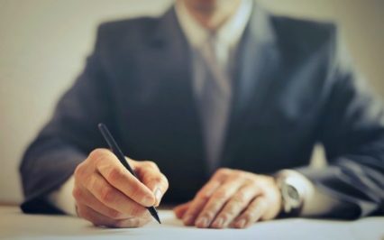 Mężczyzna w garniturze podpisuje dokument – audyt językowy dla firm