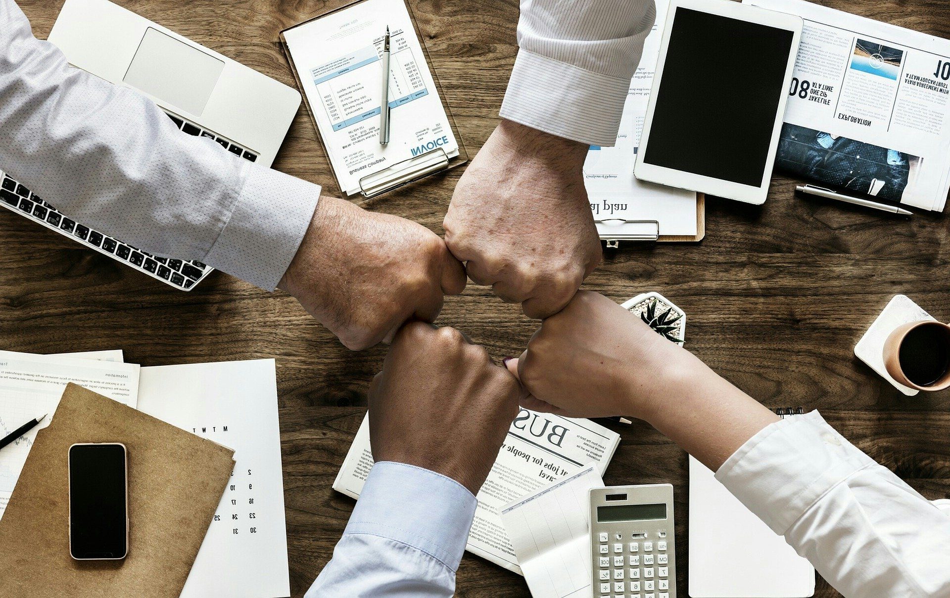 Zespół przy biurku przybija żółwika – angielski dla firm